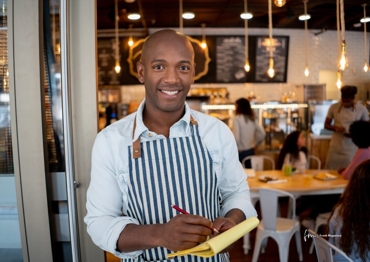 A restaurant owner taking an order at the door of his cafe